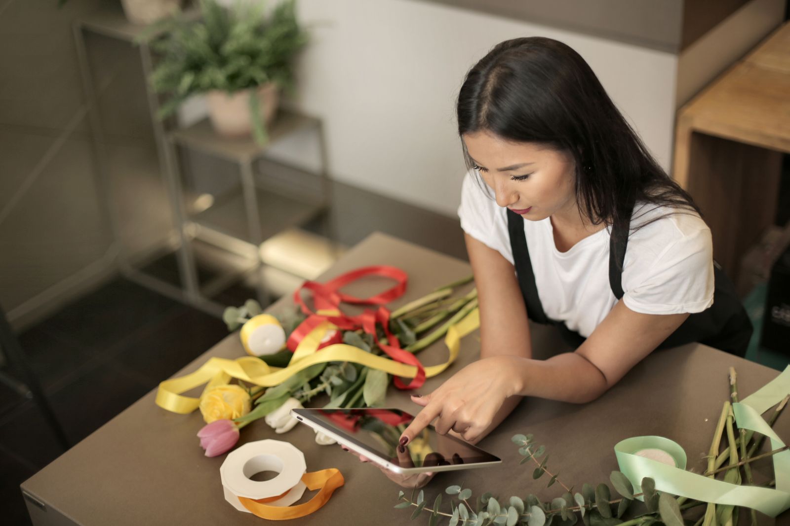 A florist checking a tablet while arranging flowers in her shop