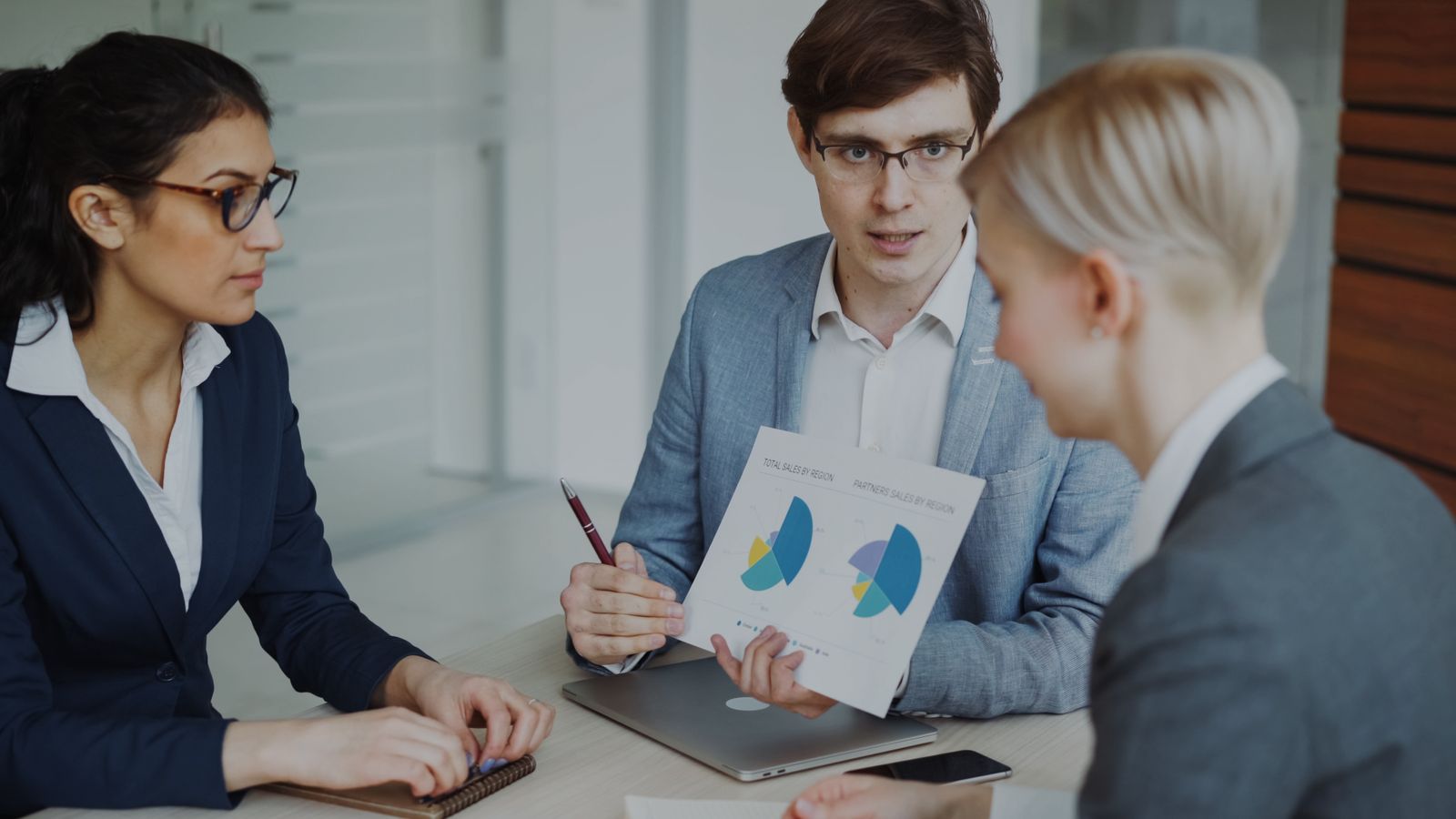 A small sales team reviewing charts on a screen during a meeting