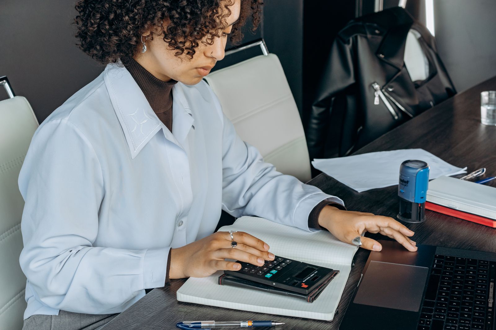 A woman working through figures with a calculator at an office desk