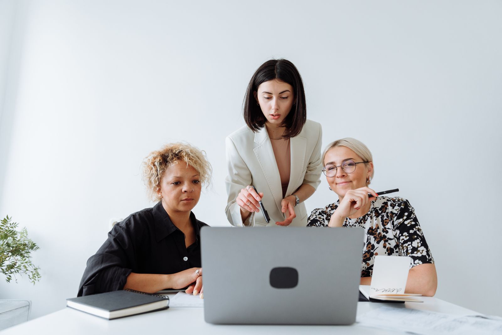 Three colleagues discussing a project around a laptop in a bright office