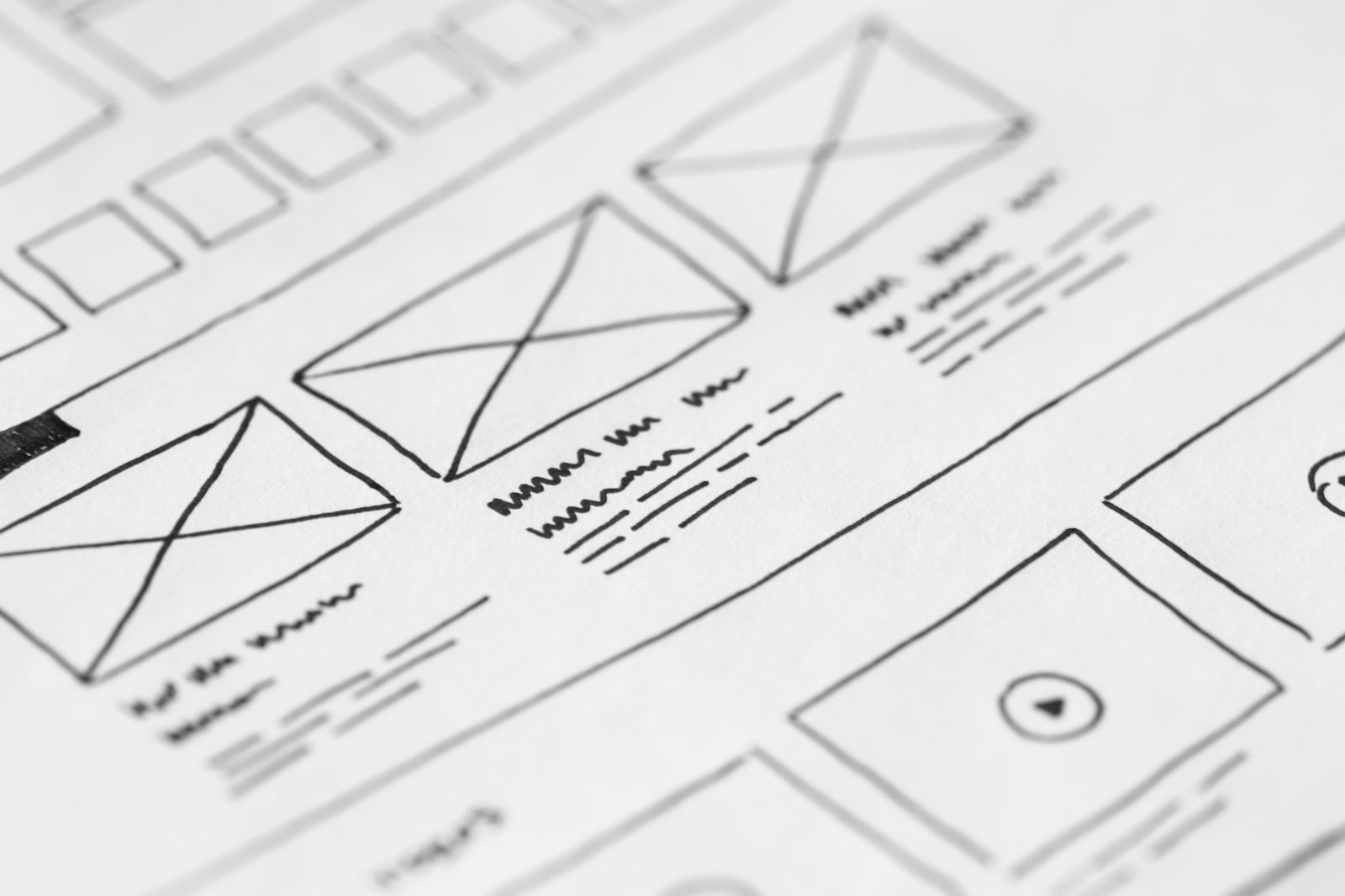 A hand-drawn website wireframe on paper with image boxes and text lines